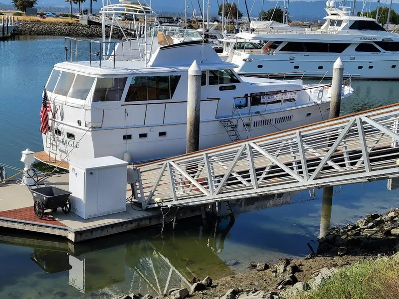 Slide: The Image of 1973 Hatteras 58 Tricabin flushdeck MY docked at marina with American flag. - 1