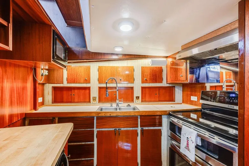 Slide: The Image of 1973 Hatteras 58 Tricabin yacht kitchen with wood cabinetry and modern appliances. - 14