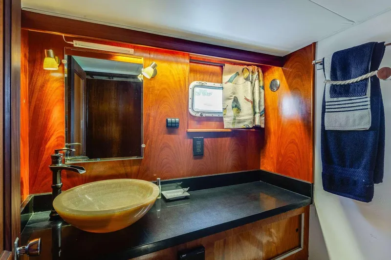 Slide: The Image of Luxurious 1973 Hatteras 58 yacht bathroom with wood paneling and modern vessel sink. - 27