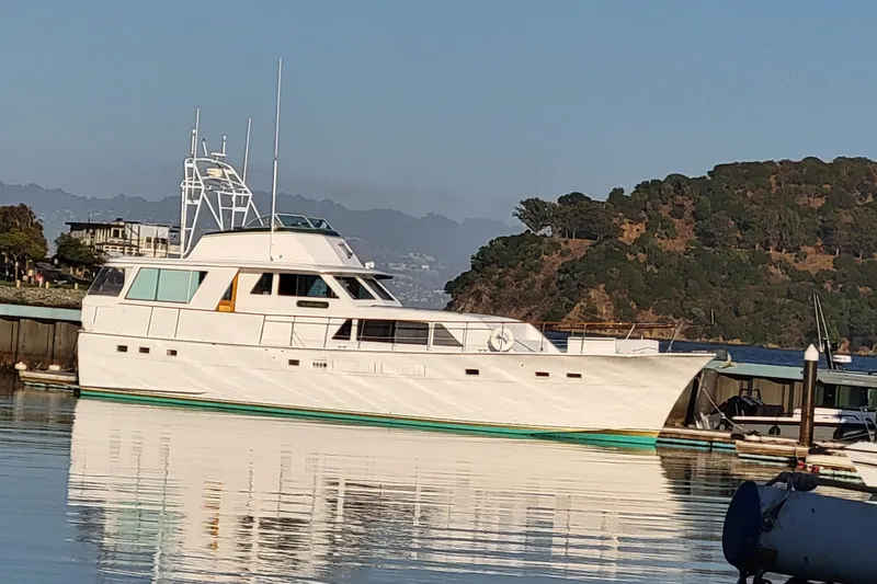 Slide: The Image of 1973 Hatteras 58 Tricabin flushdeck MY yacht docked in a scenic marina. - 3