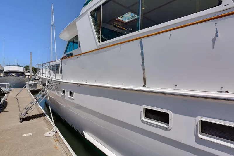 Slide: The Image of 1973 Hatteras 58 Tricabin flushdeck MY docked, showcasing sleek white exterior and windows. - 7