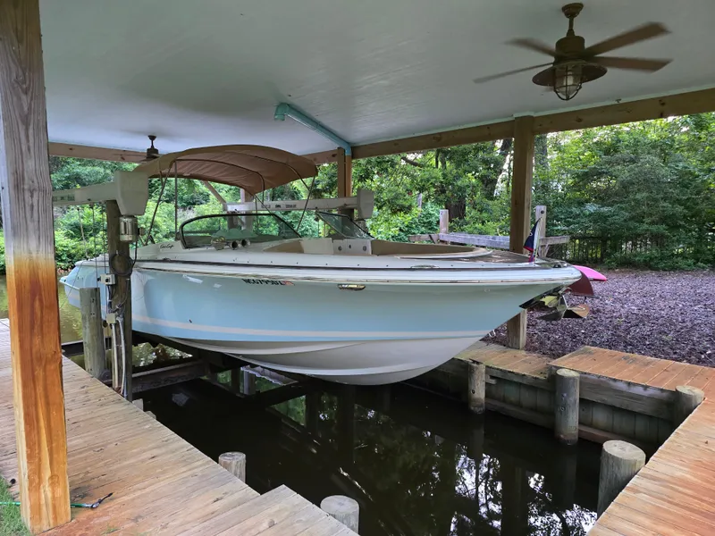 The Image of 2014 Chris-Craft Launch 28 boat docked under a covered boathouse with wooden decking. - 1