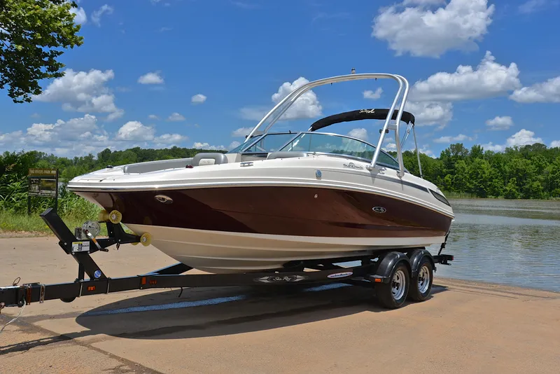 Slide: The Image of 2009 Sea Ray 210 Sundeck boat on trailer by a lake under blue sky. - 10