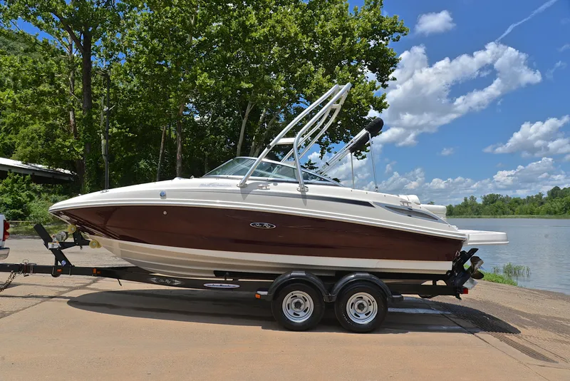 Slide: The Image of 2009 Sea Ray 210 Sundeck boat on trailer by a lake, surrounded by trees. - 11