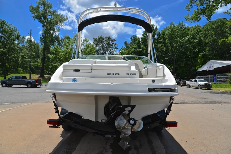 Slide: The Image of 2009 Sea Ray 210 Sundeck boat on trailer, parked outdoors with trees and vehicles nearby. - 13