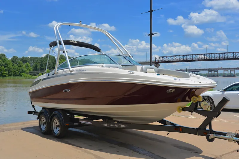 Slide: The Image of 2009 Sea Ray 210 Sundeck boat on trailer by river, under blue sky. - 16
