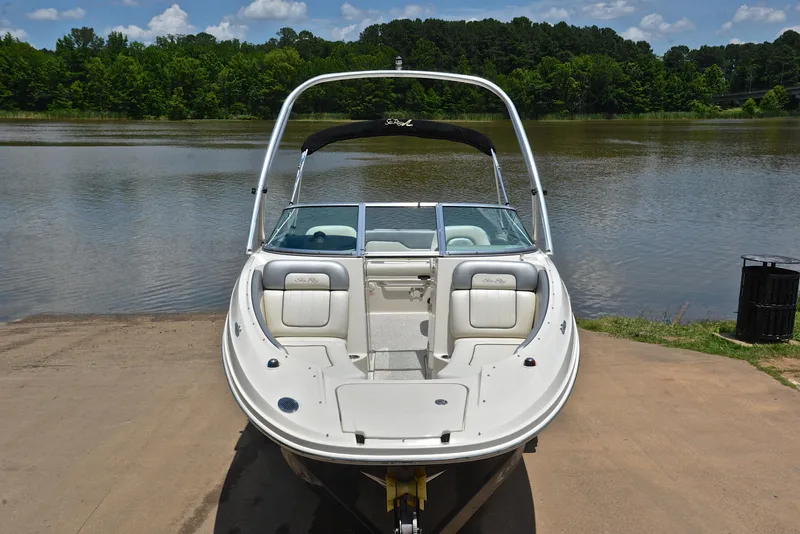 Slide: The Image of 2009 Sea Ray 210 Sundeck boat on a lake shore, surrounded by lush greenery. - 17