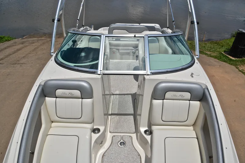 Slide: The Image of 2009 Sea Ray 210 Sundeck boat interior with seating and windshield, docked by the water. - 20