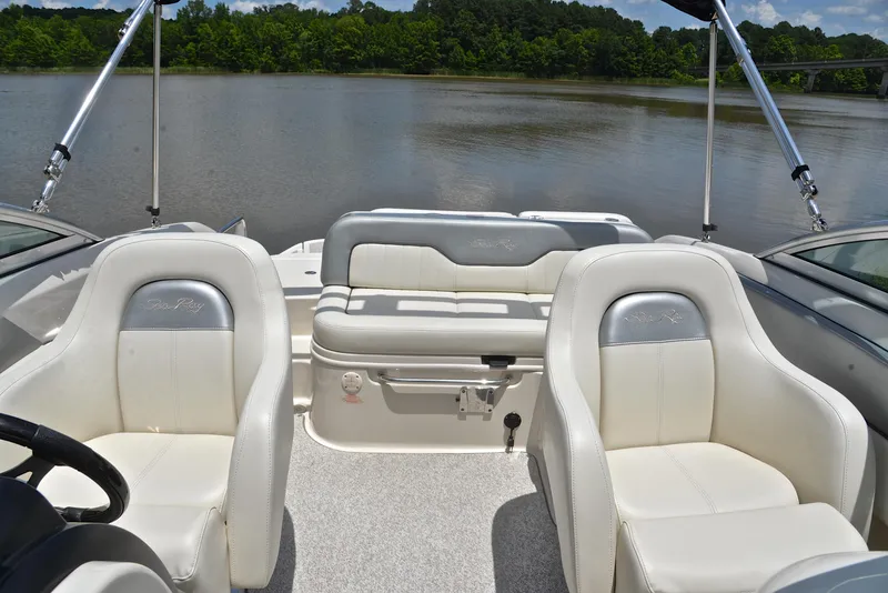 Slide: The Image of 2009 Sea Ray 210 Sundeck interior with white seating, on a calm lake background. - 22