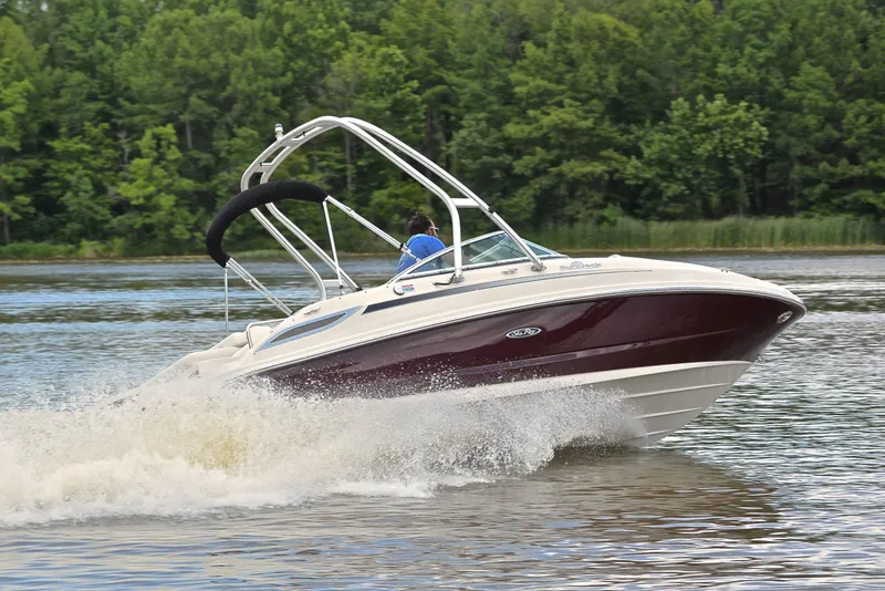 Slide: The Image of 2009 Sea Ray 210 Sundeck speeding on a lake with lush green forest backdrop. - 5