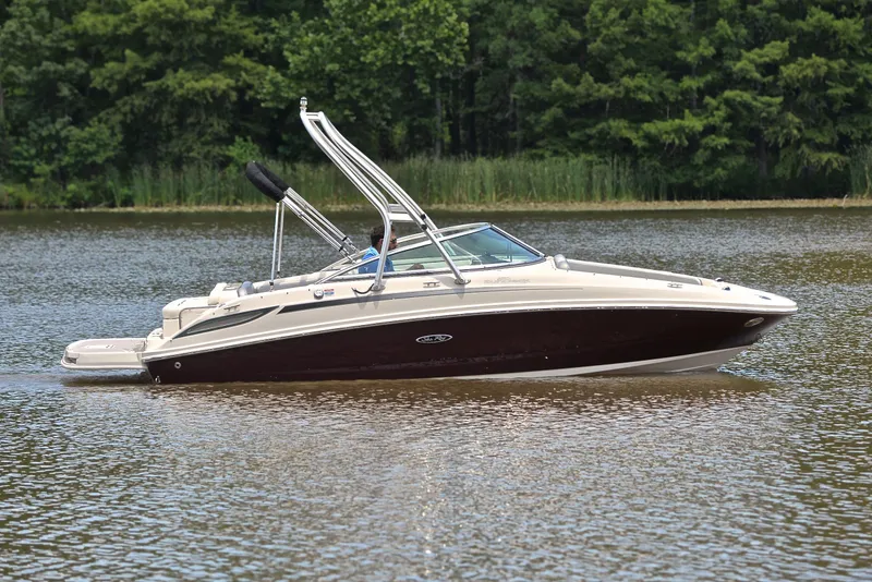 Slide: The Image of 2009 Sea Ray 210 Sundeck boat cruising on a calm lake with forest backdrop. - 7