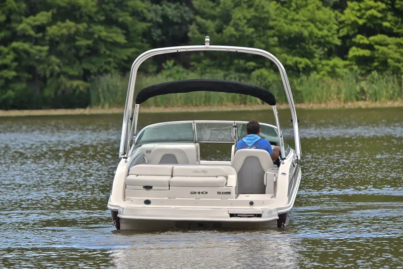 Slide: The Image of 2009 Sea Ray 210 Sundeck boat cruising on a calm lake with lush green trees. - 8