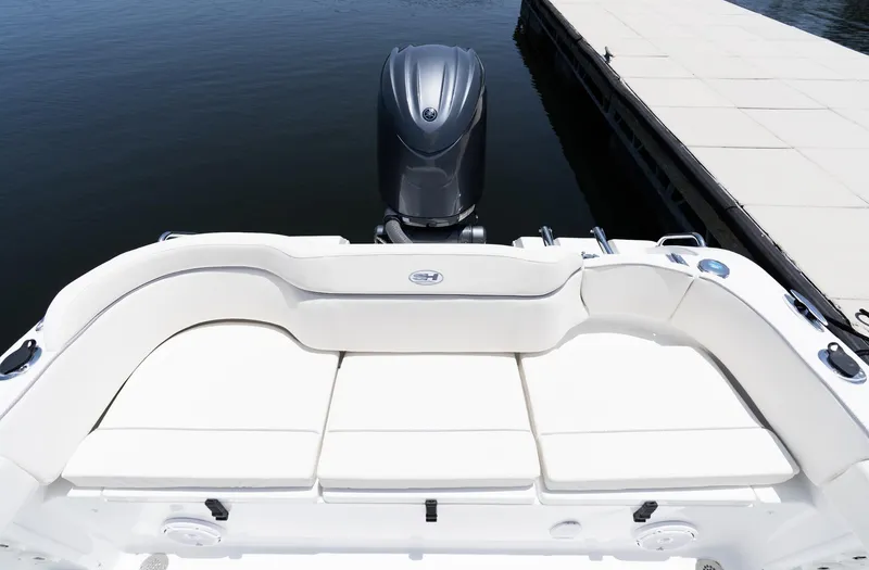 Slide: The Image of 2025 Sea Hunt Ultra 219 boat with cushioned seating and outboard motor at dock. - 11