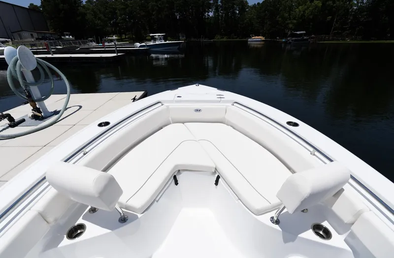 Slide: The Image of 2025 Sea Hunt Ultra 219 boat with white seating, docked by a serene lake. - 16