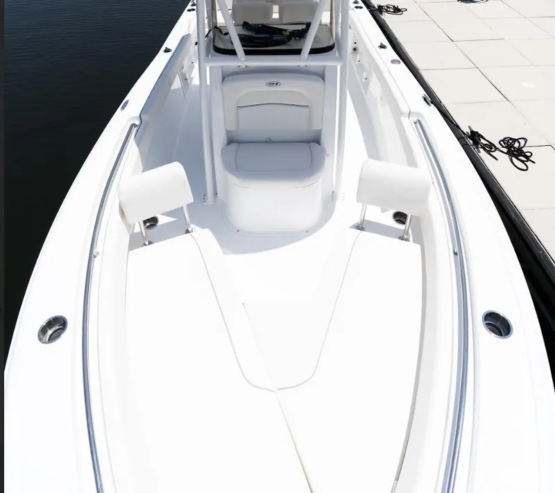 Slide: The Image of 2025 Sea Hunt Ultra 219 boat interior, sleek white design, docked by the water. - 20
