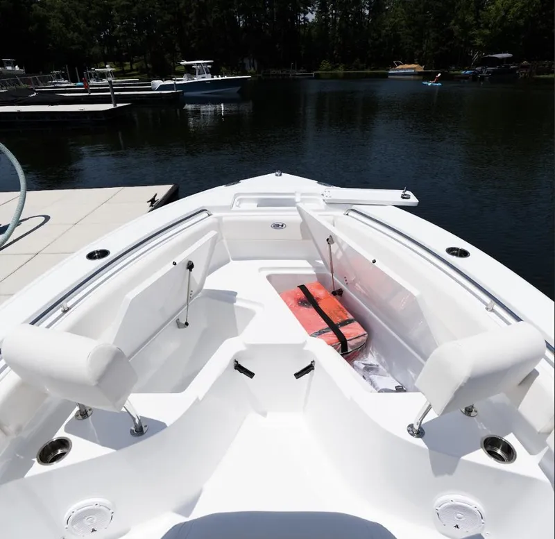 Slide: The Image of 2025 Sea Hunt Ultra 219 boat interior with seating and storage, docked on a calm lake. - 24