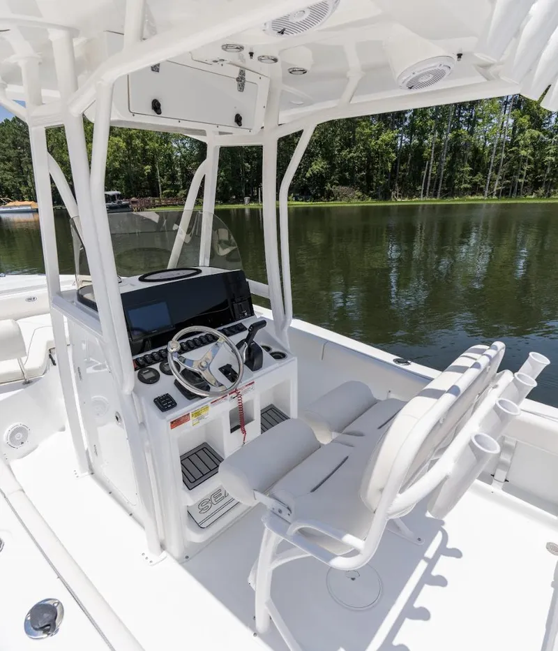 Slide: The Image of 2025 Sea Hunt Ultra 219 boat interior with steering console on a calm lake. - 25