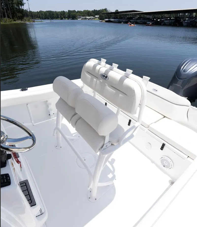 Slide: The Image of 2025 Sea Hunt Ultra 219 boat interior with white seating, steering wheel, and lake view. - 29