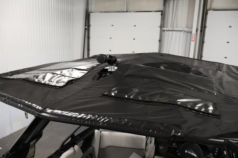 Slide: The Image of 2026 Centurion Ri245 boat with black canopy in a garage setting. - 44