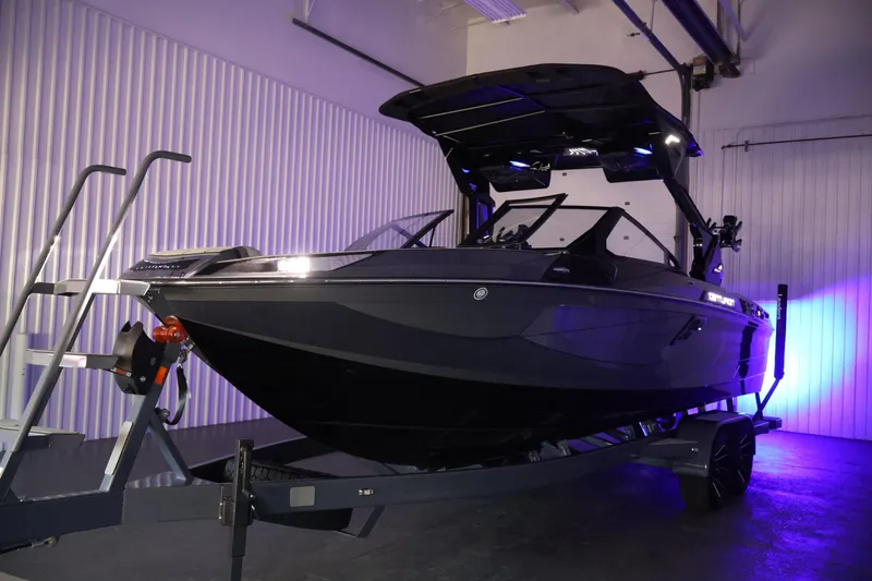 Slide: The Image of 2026 Centurion Ri245 boat on trailer in indoor showroom with blue lighting. - 60