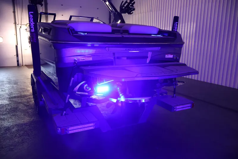 Slide: The Image of 2026 Centurion Ri245 boat with vibrant blue LED lighting in a garage setting. - 62