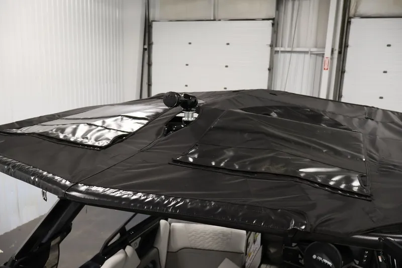Slide: The Image of 2026 Centurion Ri245 boat with black canopy in a garage setting. - 38