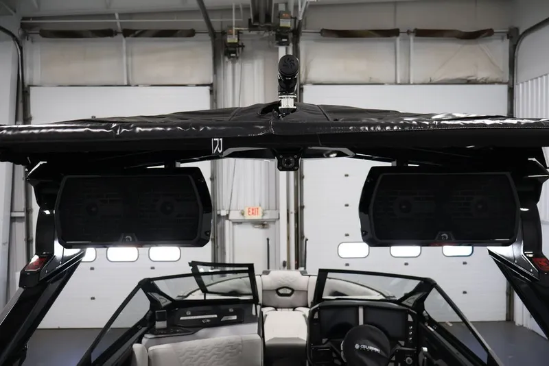 Slide: The Image of 2026 Centurion Ri245 boat interior with speakers and black canopy in a garage setting. - 43