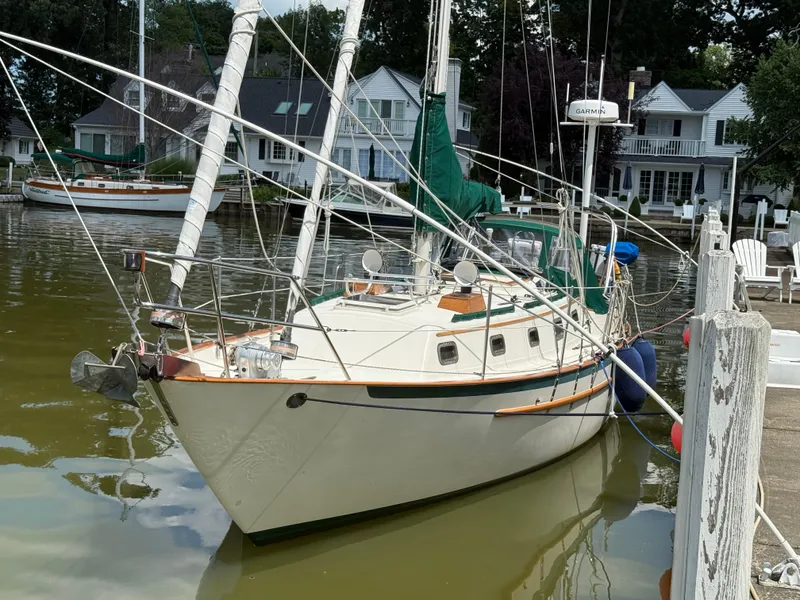 The Image of 1995 Pacific Seacraft 34 sailboat anchored on a calm lake with lush green trees. - 0