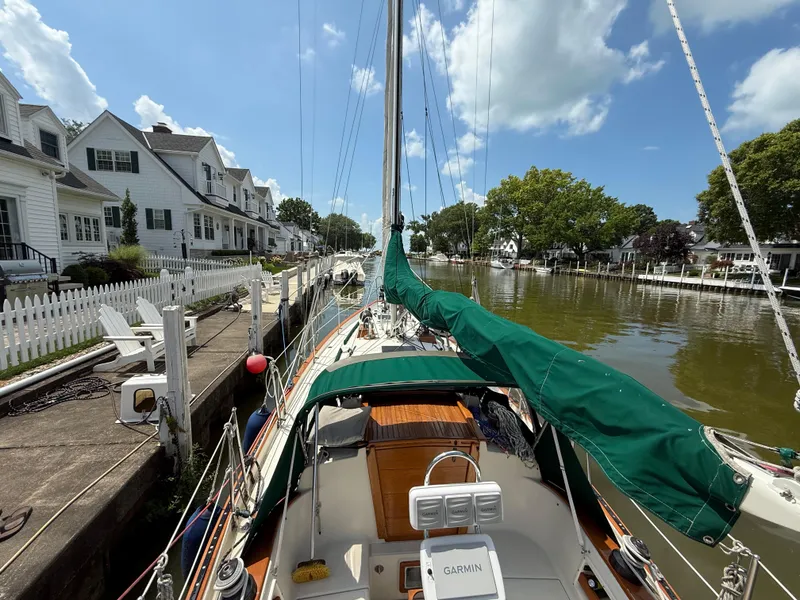 Slide: The Image of 1994 Pacific Seacraft 34 sailboat docked, featuring green sail cover and Garmin navigation system. - 12