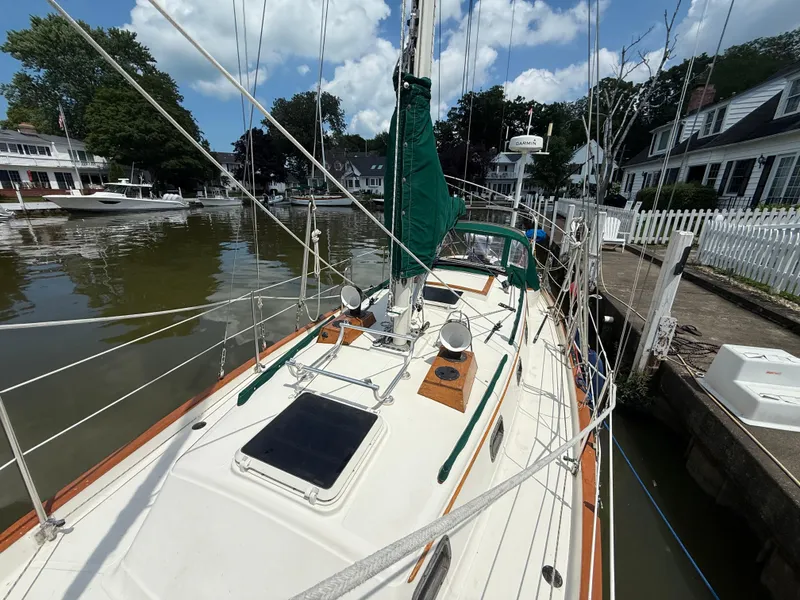 Slide: The Image of Sailboat docked by waterfront homes, Pacific Seacraft 34, 1994 model, under a clear blue sky. - 3
