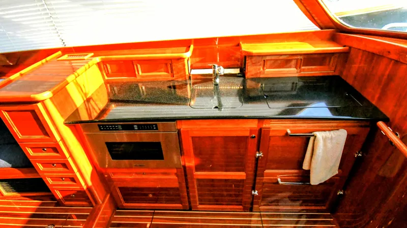 Slide: The Image of Luxurious 2022 Hinckley Talaria 43 yacht kitchen with sleek wood cabinetry and modern appliances. - 10