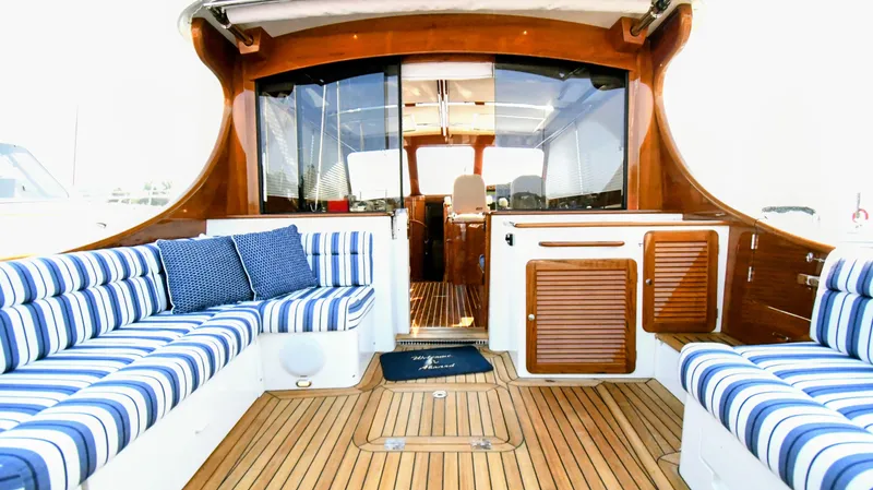 Slide: The Image of Luxurious 2022 Hinckley Talaria 43 yacht interior with striped seating and wooden finishes. - 2