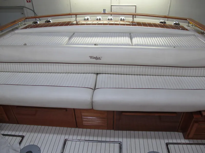 Slide: The Image of 1991 Windsor Craft 310 boat interior with white cushioned seating and wooden accents. - 13