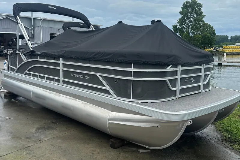 Slide: The Image of 2024 Bennington SV 22 Swingback pontoon boat with black cover, docked near water. - 10