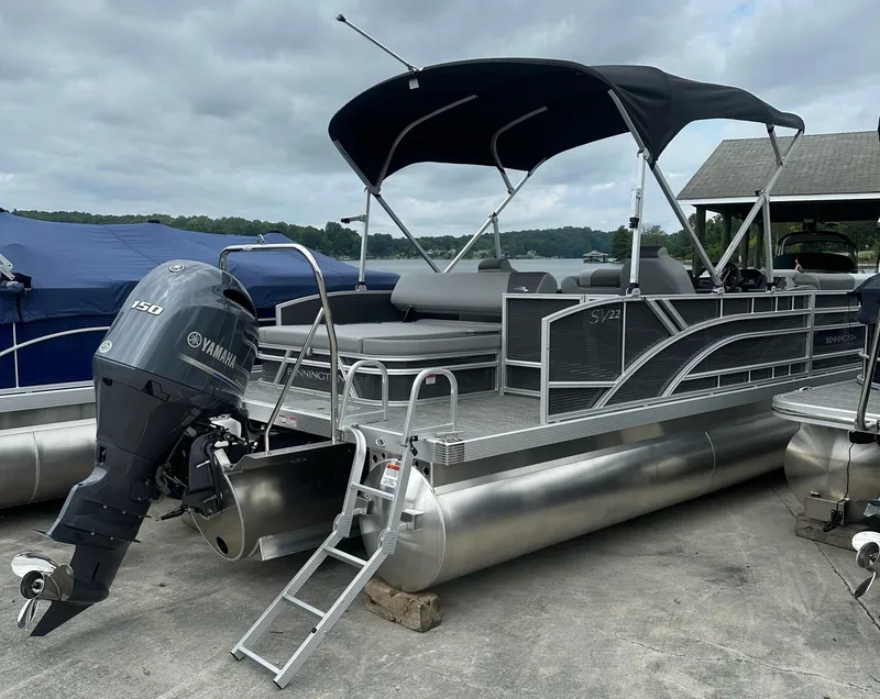 Slide: The Image of 2024 Bennington SV 22 Swingback pontoon boat with Yamaha 150 engine, docked under cloudy skies. - 3