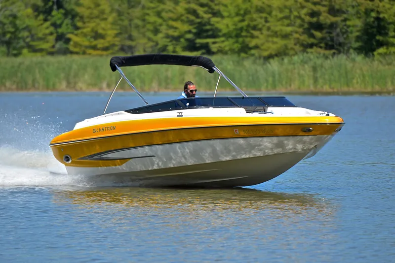 The Image of 2007 Glastron GXL 235 speedboat cruising on a lake with lush greenery. - 1