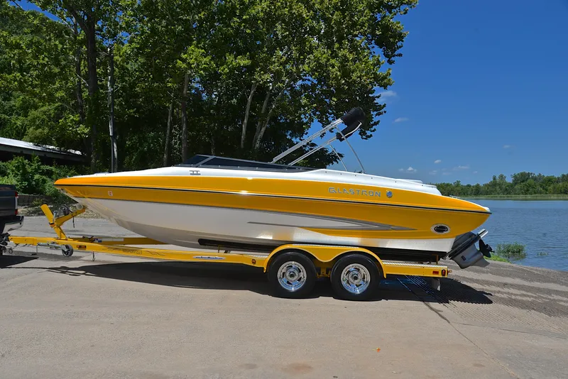 Slide: The Image of 2007 Glastron GXL 235 boat on trailer by a lake, under clear blue sky. - 10