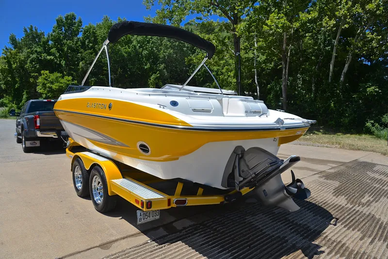 Slide: The Image of 2007 Glastron GXL 235 boat in yellow on trailer, parked near trees. - 11