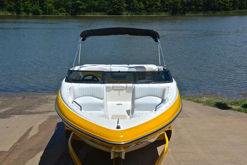 Slide: The Image of 2007 Glastron GXL 235 boat with yellow hull, docked by a serene lake. - 16