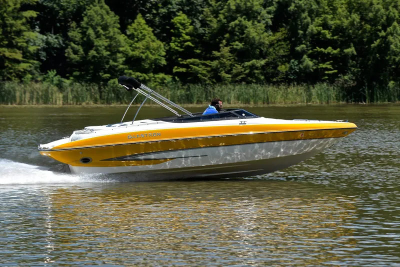 Slide: The Image of 2007 Glastron GXL 235 speedboat cruising on a lake with lush green trees. - 3
