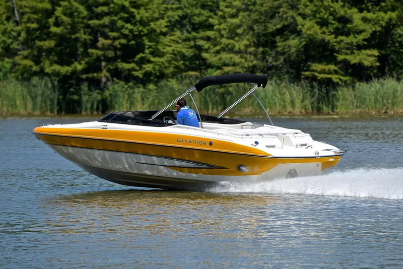 Slide: The Image of 2007 Glastron GXL 235 boat cruising on a lake with lush green background. - 4