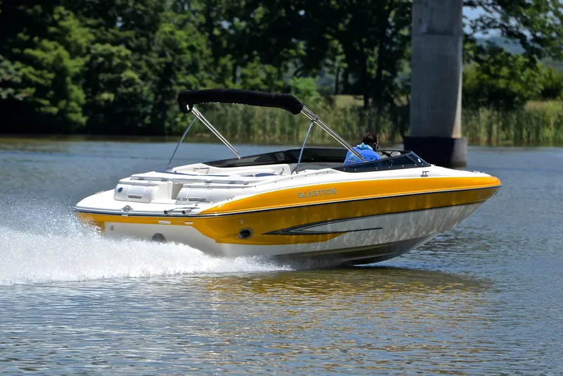 Slide: The Image of 2007 Glastron GXL 235 speedboat cruising on a lake with lush greenery. - 5