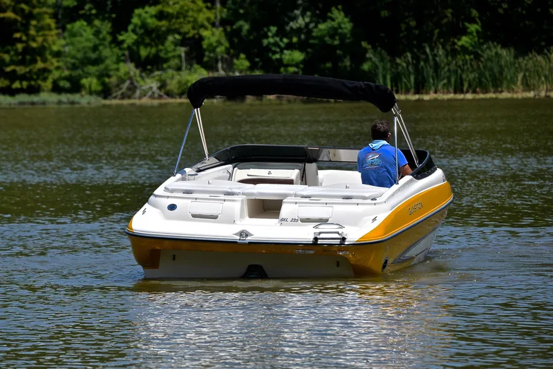 Slide: The Image of 2007 Glastron GXL 235 boat cruising on a calm lake with lush green background. - 7