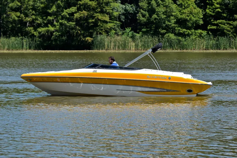 Slide: The Image of 2007 Glastron GXL 235 boat cruising on a calm lake with lush greenery. - 8