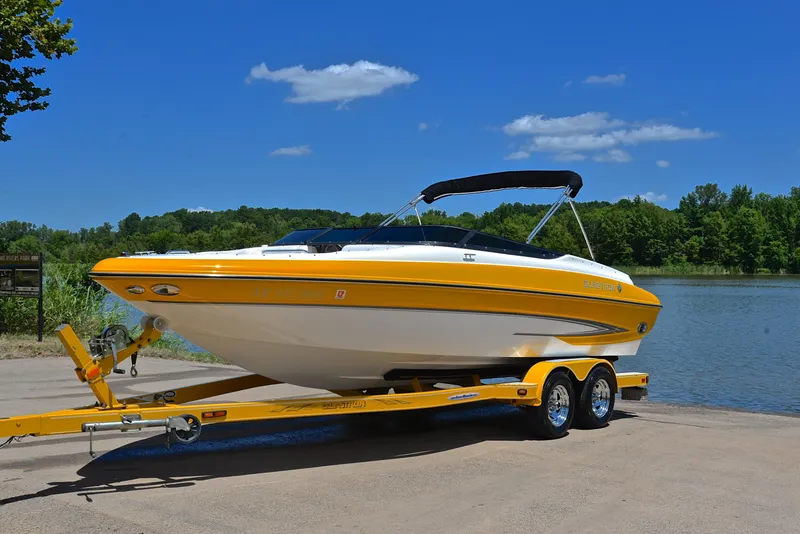 Slide: The Image of 2007 Glastron GXL 235 boat on trailer by a lake, under clear blue sky. - 9