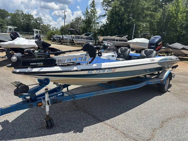 Slide: The Image of 2000 Triton TR20 boat on trailer, equipped with Minn Kota motor, parked outdoors. - 13