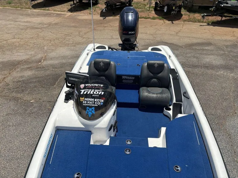 Slide: The Image of 2000 Triton TR20 boat with blue interior and motor, parked on pavement. - 15
