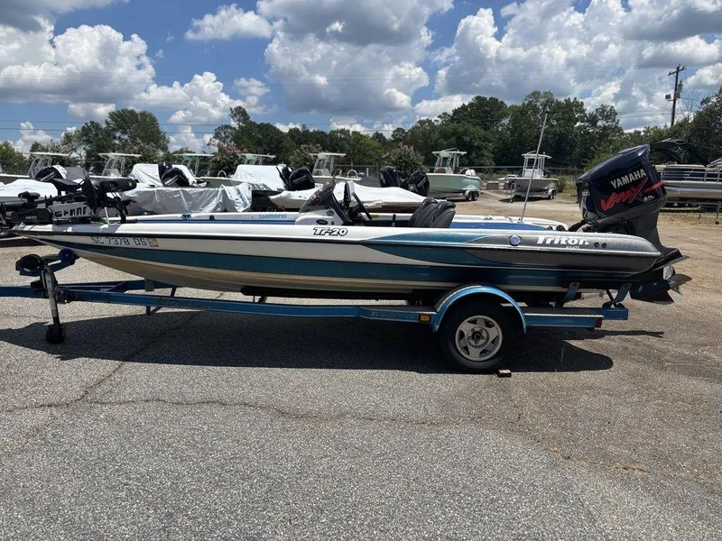 Slide: The Image of 2000 Triton TR20 boat on trailer, Yamaha motor, parked outdoors under cloudy sky. - 6