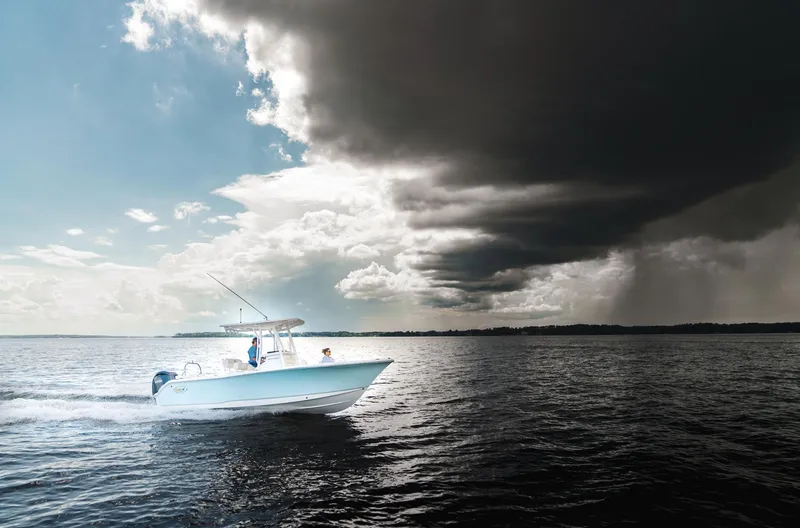 Slide: The Image of 2025 Sea Hunt Ultra 229 boat navigating under dramatic stormy skies. - 14