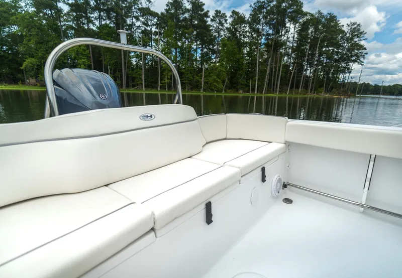 Slide: The Image of 2025 Sea Hunt Ultra 229 boat interior with white seating, lake view, and trees in background. - 21